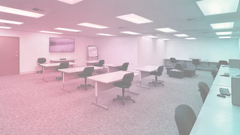 Empty computer lab with desks facing wall monitor